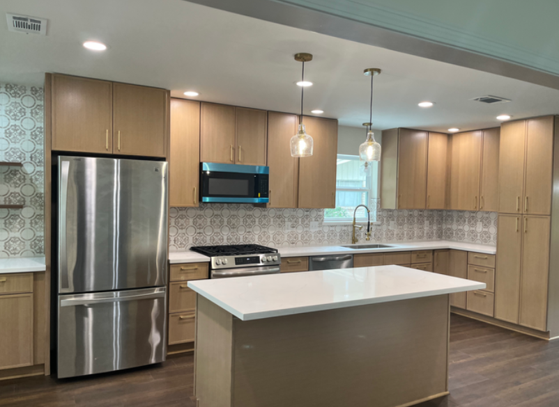 Completed modern kitchen renovation with new cabinets, island, backsplash, and lighting